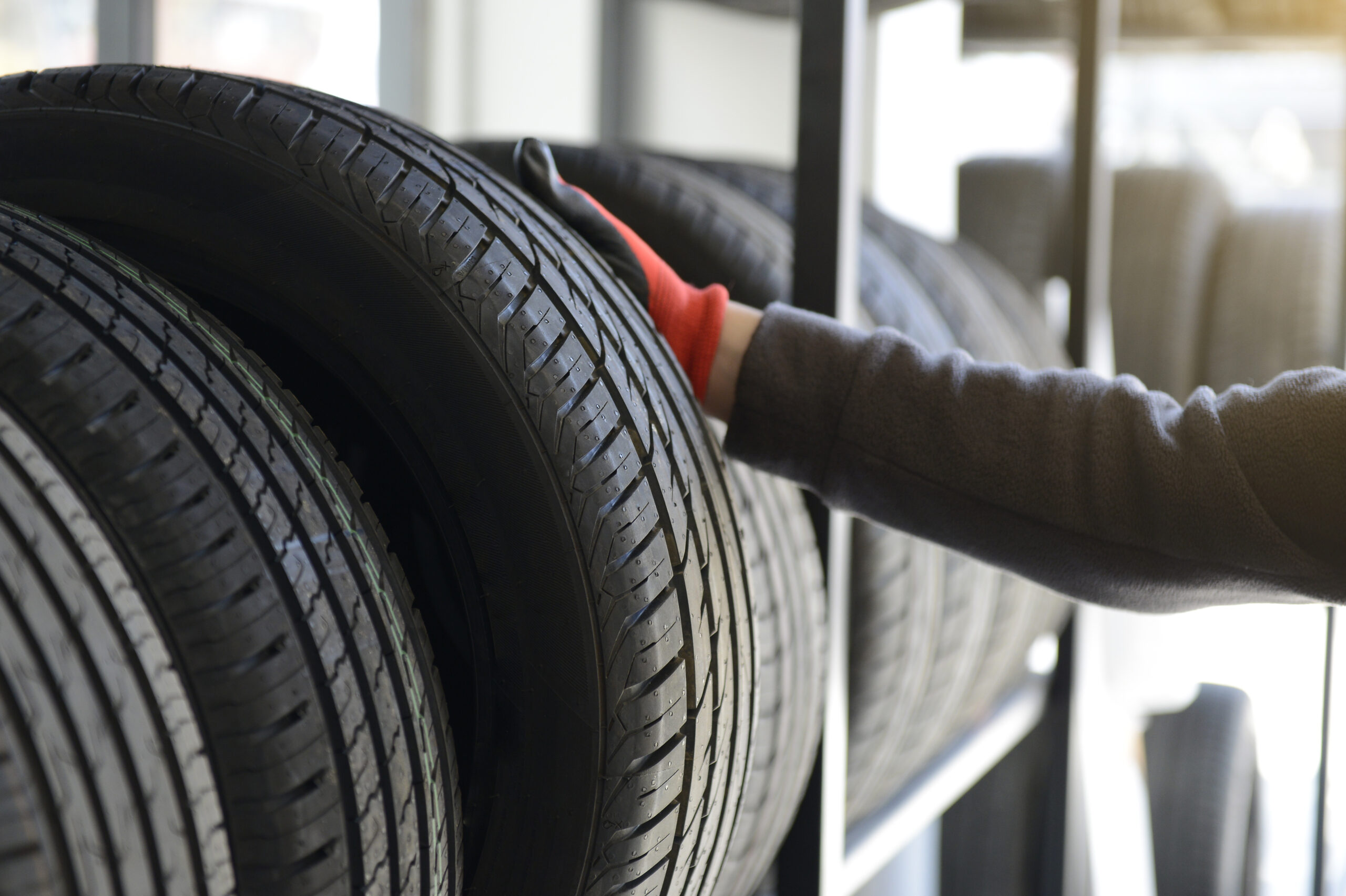 Male mechanic holding tire while repairing service garage