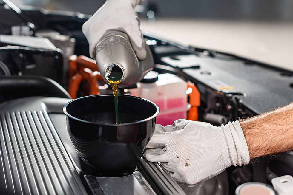 a person is pouring the oil into the car